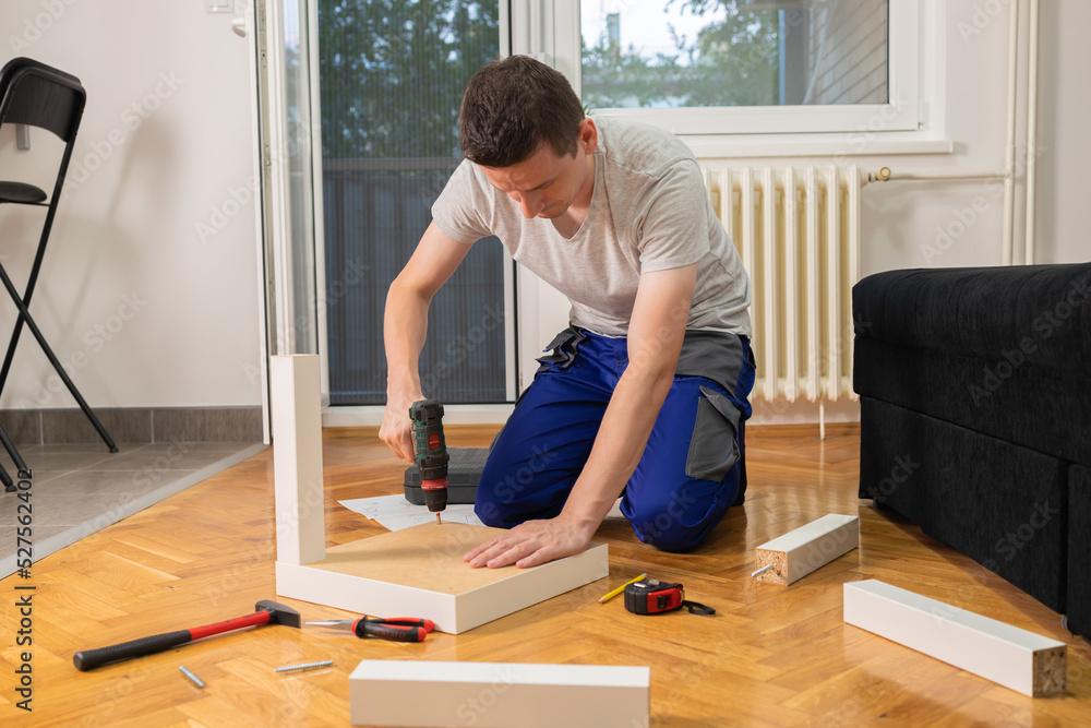 Man assembling furniture at home. Handyman is engaged in assembling the coffee table.. Man assembling furniture at home. Handyman is engaged in assembling the coffee table..