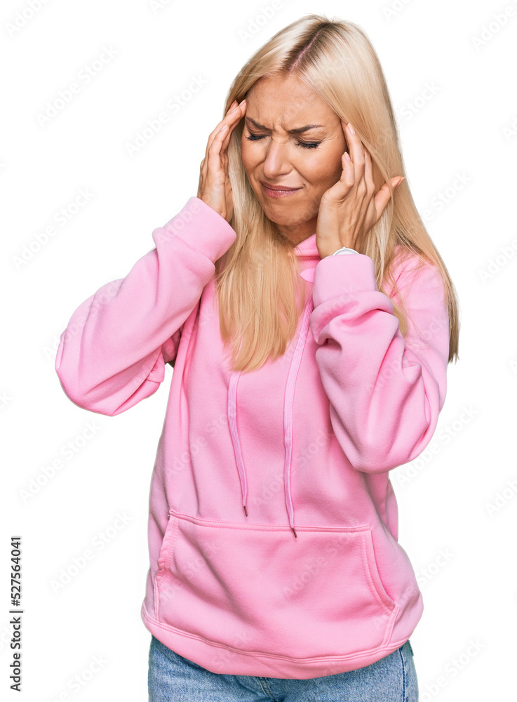 Young blonde woman wearing casual sweatshirt with hand on head, headache because stress. suffering migraine. Young blonde woman wearing casual sweatshirt with hand on head, headache because stress. suffering migraine.