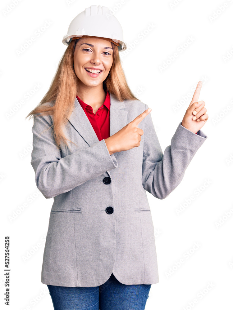 Beautiful young woman wearing architect hardhat smiling and looking at the camera pointing with two hands and fingers to the side. Beautiful young woman wearing architect hardhat smiling and looking at the camera pointing with two hands and fingers to the side.