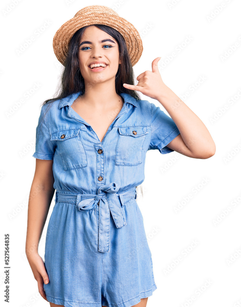Brunette teenager girl wearing summer hat smiling doing phone gesture with hand and fingers like talking on the telephone. communicating concepts. Brunette teenager girl wearing summer hat smiling doing phone gesture with hand and fingers like talking on the telephone. communicating concepts.