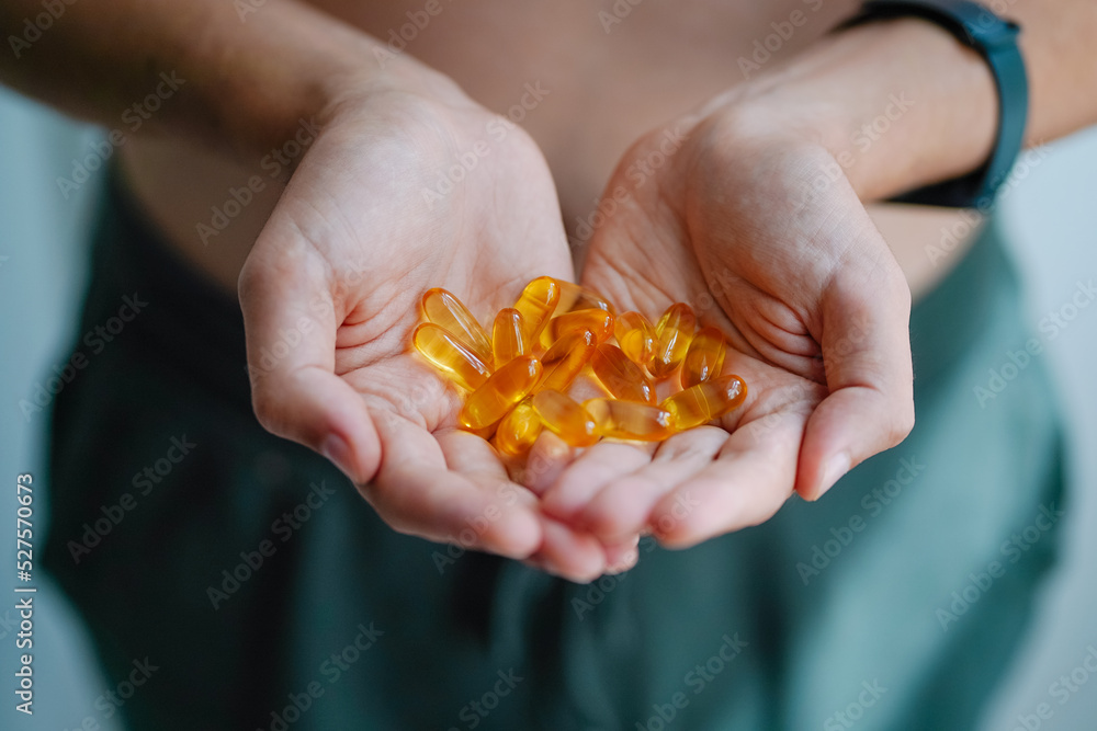 A handful of vitamins in the hands of a young man. Bright Omega-3 capsules. Medicinal product of animal origin. Fish oil source of vitamins A and D A handful of vitamins in the hands of a young man. Bright Omega-3 capsules. Medicinal product of animal origin. Fish oil source of vitamins A and D