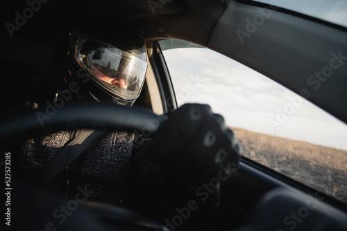 Rally car driver sitting by the steering wheel in the sunset rays concept. © Dmitriy
