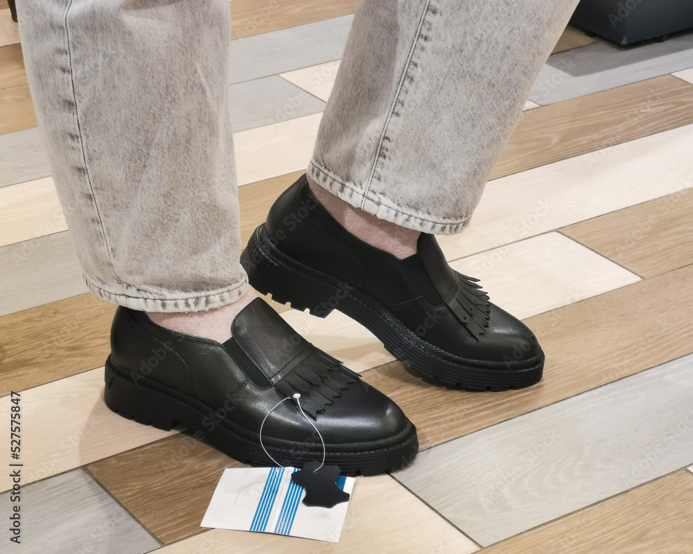 Legs of a young woman in fashionable black leather shoes. Trying on stylish loafers in a shoe store. New fashion collection of shoes. Legs of a young woman in fashionable black leather shoes. Trying on stylish loafers in a shoe store. New fashion collection of shoes.