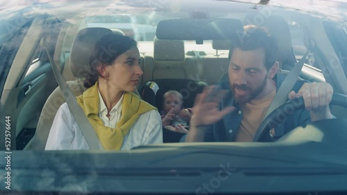 Footage of beautiful young Caucasian couple having argument, gesturing in morning. Family fight. Littlie baby boy sitting in baby car seat in background. Trip, child care, protection, safe