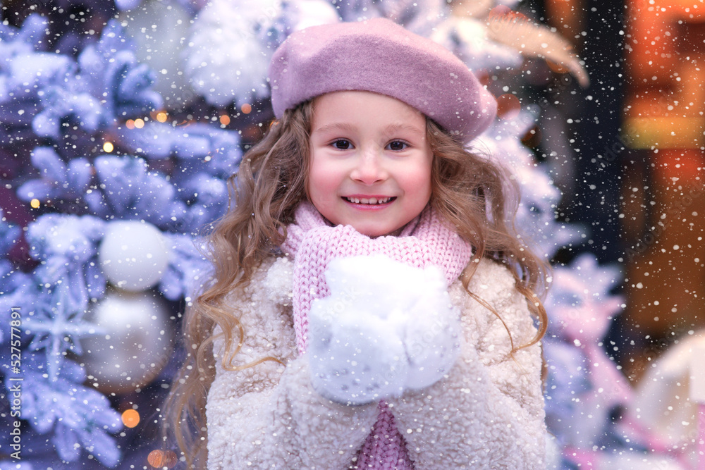 Portrait of beautiful adorable happy kid girl, little cute cheerful positive child is smiling laughing having fun outdoors at winter snow day in hat, gloves and scarf looking at camera. Christmas tree Portrait of beautiful adorable happy kid girl, little cute cheerful positive child is smiling laughing having fun outdoors at winter snow day in hat, gloves and scarf looking at camera. Christmas tree