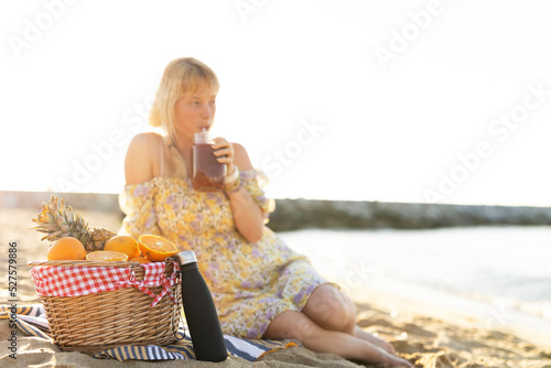 Cheerful young woman enjoy at tropical sand beach. Girl drinking juice. photo