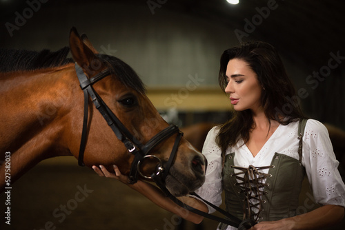 Foto Young beautiful girl with the horse in the stable.