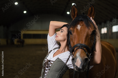 Young beautiful girl with the horse in the stable.