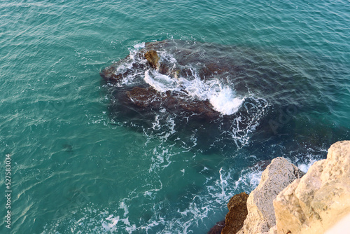 top view of a rock in the sea against which the sea waves crash