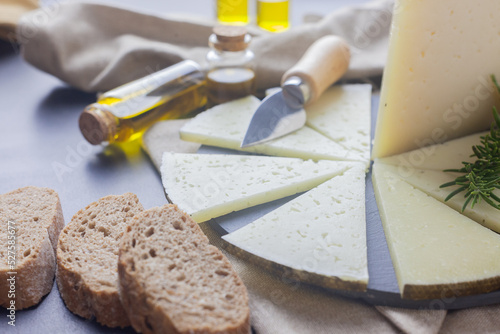 Fotografie Lonchas de queso curado manchego en un plato y con unos frascos de aceite de oli