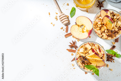 Apple Pie Granola Cheesecake, breakfast snack layered dessert with oat granola, cream cheese yogurt, honey, apple slices and cinnamon spices on white background copy space