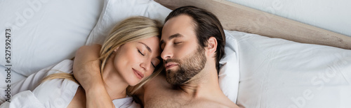 top view of blonde woman and brunette man sleeping on bed in morning, banner.