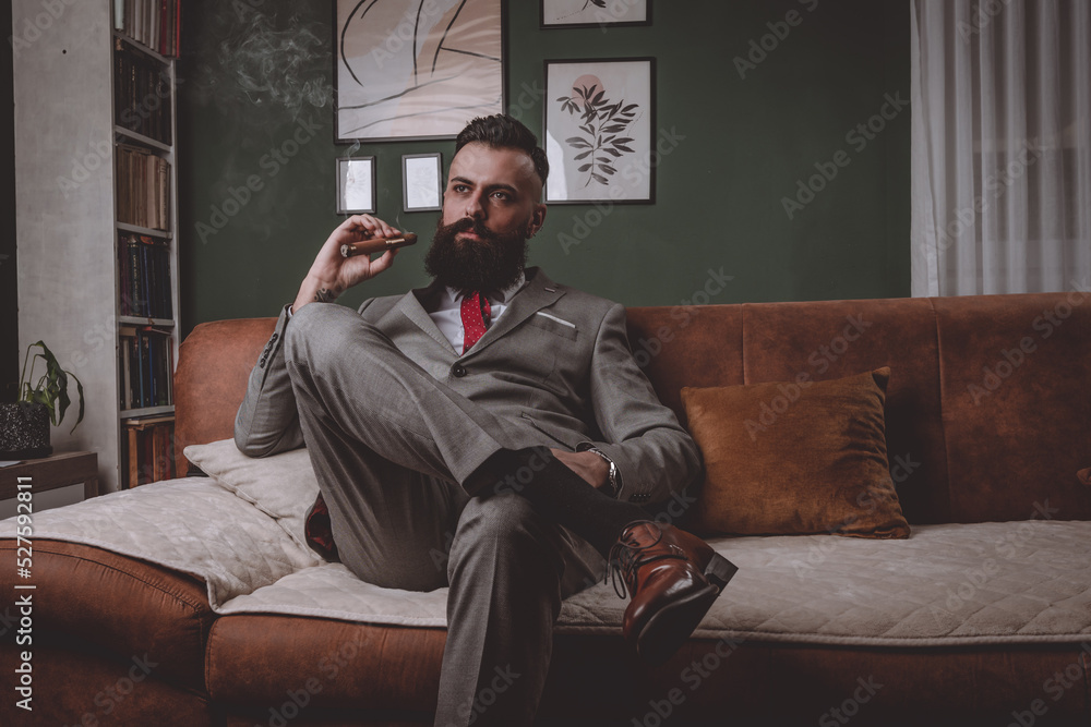businessman in a grey suit smoking cigar businessman in a grey suit smoking cigar