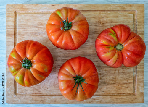 Photos quatre tomates coeur de boeuf sur une planche à découper