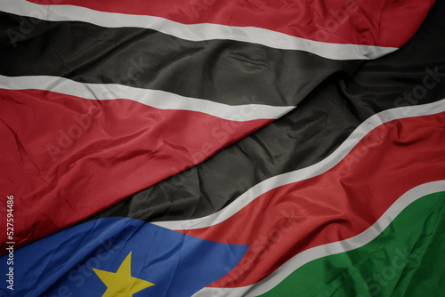 waving colorful flag of south sudan and national flag of trinidad and tobago.