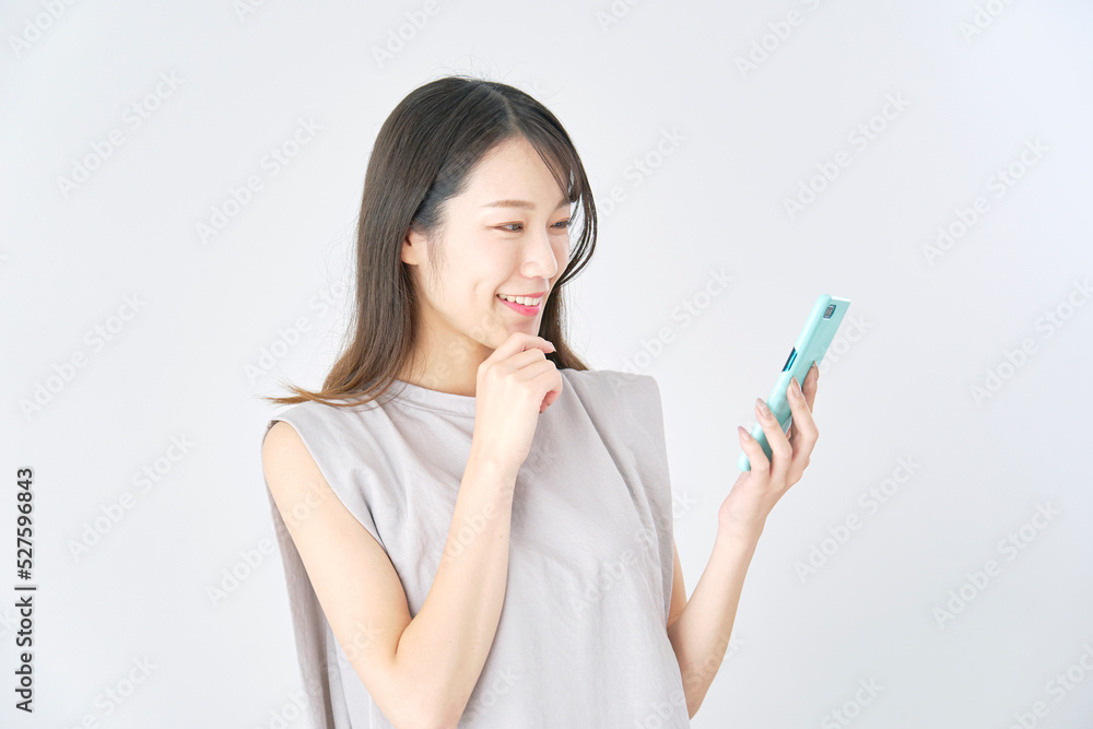 白背景でスマホを笑顔で見る女性