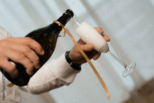 a man pours champagne into a glass. closeup of a hand