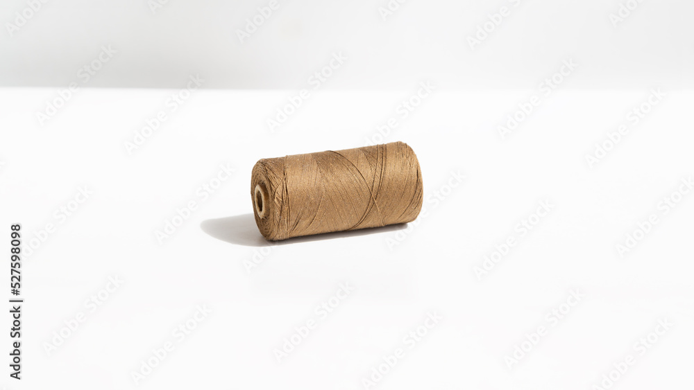 Spool of light brown threads on a white background