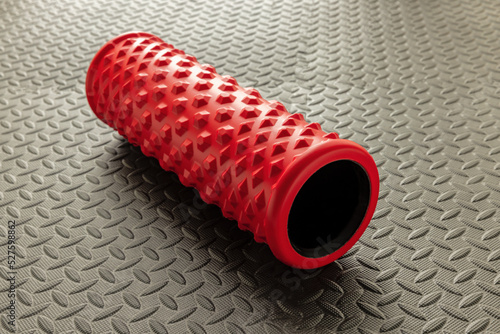 Red foam roller for deep tissue and muscle massage and myofascial trigger point release  on black mat  photo