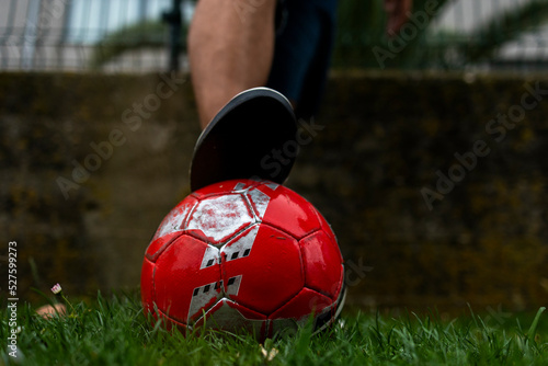 A man's foot in a sneaker on a soccer ball on green grass.