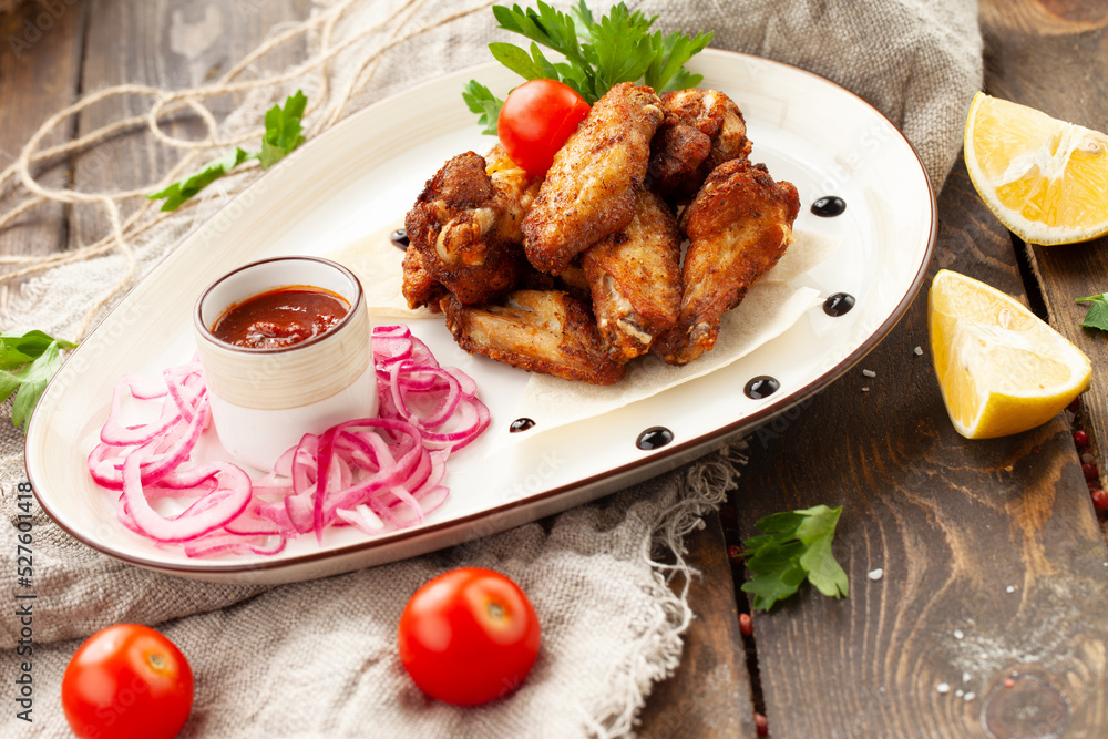 Fried chicken wings and legs in a plate on a wooden table. Fried chicken wings and legs in a plate on a wooden table.