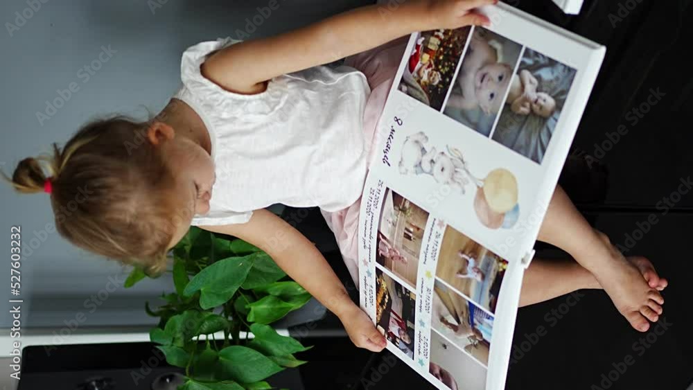 Happy cute little girl looking at photos in album. Happy smiling daughter browsing through printed family album, looking at pictures. Happy cute little girl looking at photos in album. Happy smiling daughter browsing through printed family album, looking at pictures.