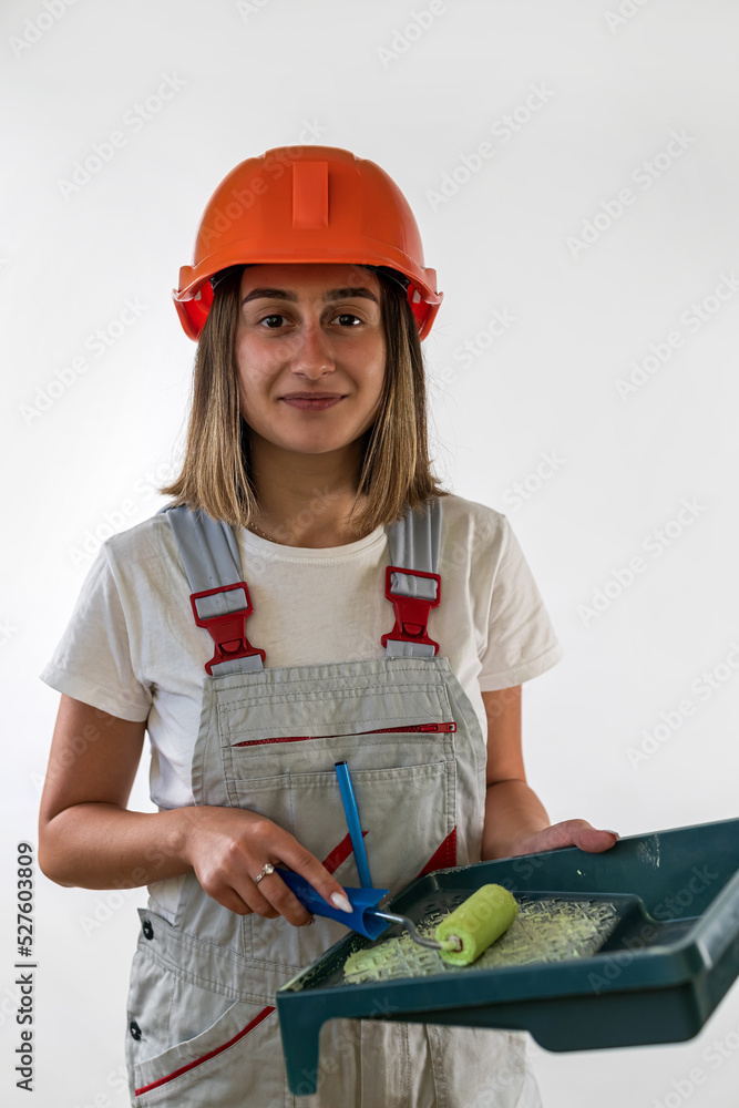 female builder working with roller for painting wall and has a confident expression on her face