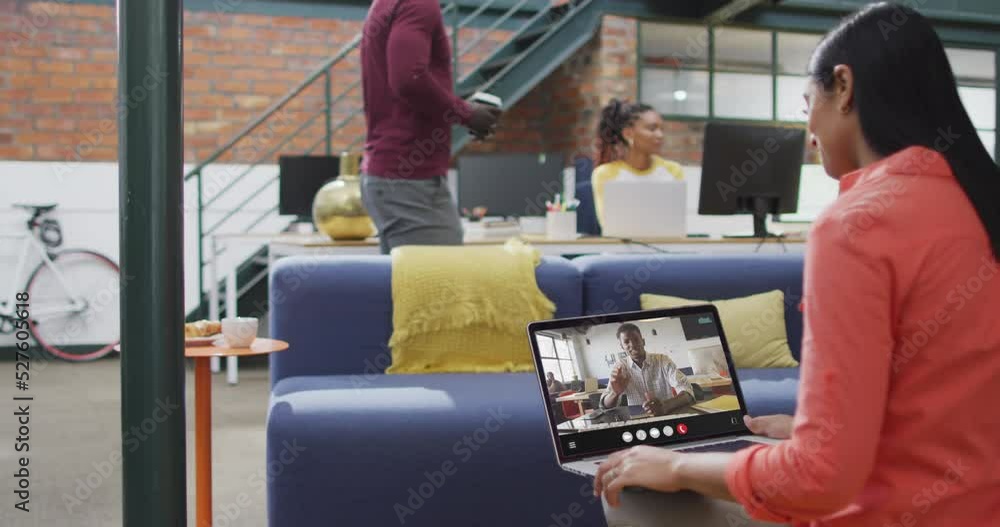 Biracial woman using laptop for video call, with business colleague on screen