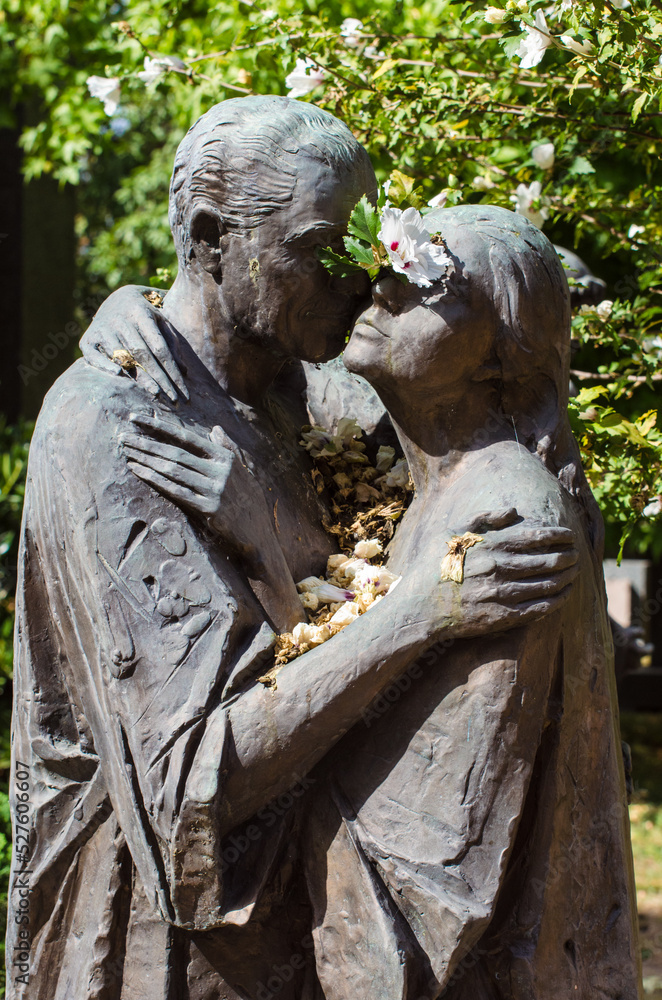 Una coppia di amanti abbracciati e coperti di petali di fiori su una tomba del cimitero maggiore di Milano Una coppia di amanti abbracciati e coperti di petali di fiori su una tomba del cimitero maggiore di Milano