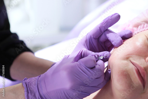 Injections for the face. The filler is inserted into the cheekbones. Maintaining beauty. Cosmetic clinic.The cosmetologist makes a filler injection. Anti-aging cosmetic procedure.Collagen.