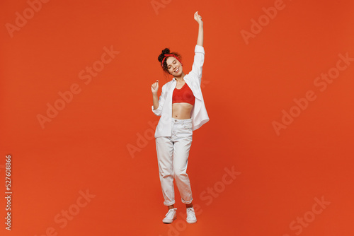 Full body young smiling happy cheerful cool woman of African American ethnicity 20s wearing white shirt top dance raise up hands have fun isolated on plain orange background. People lifestyle concept.