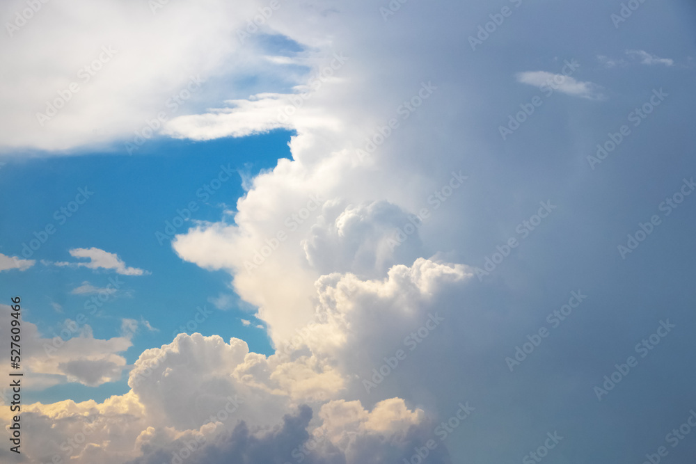 Fluffy white clouds are illuminated by the evening sun in the blue sky Fluffy white clouds are illuminated by the evening sun in the blue sky