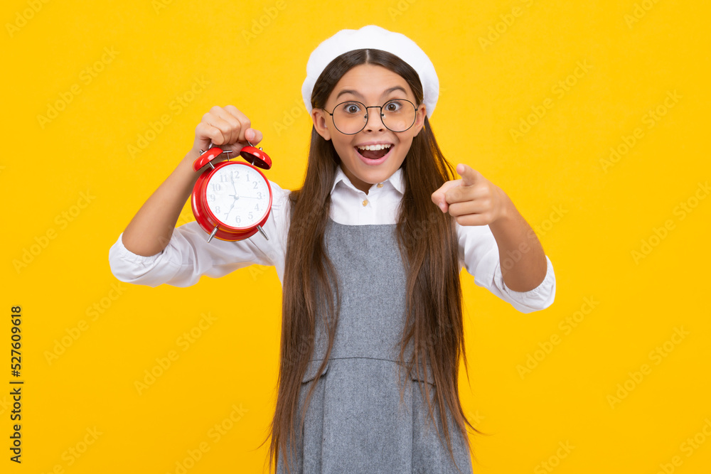 Child student girl with clock isolated on yellow background. Child back to school. Education and time concept. Excited face, cheerful emotions of teenager girl. Child student girl with clock isolated on yellow background. Child back to school. Education and time concept. Excited face, cheerful emotions of teenager girl.