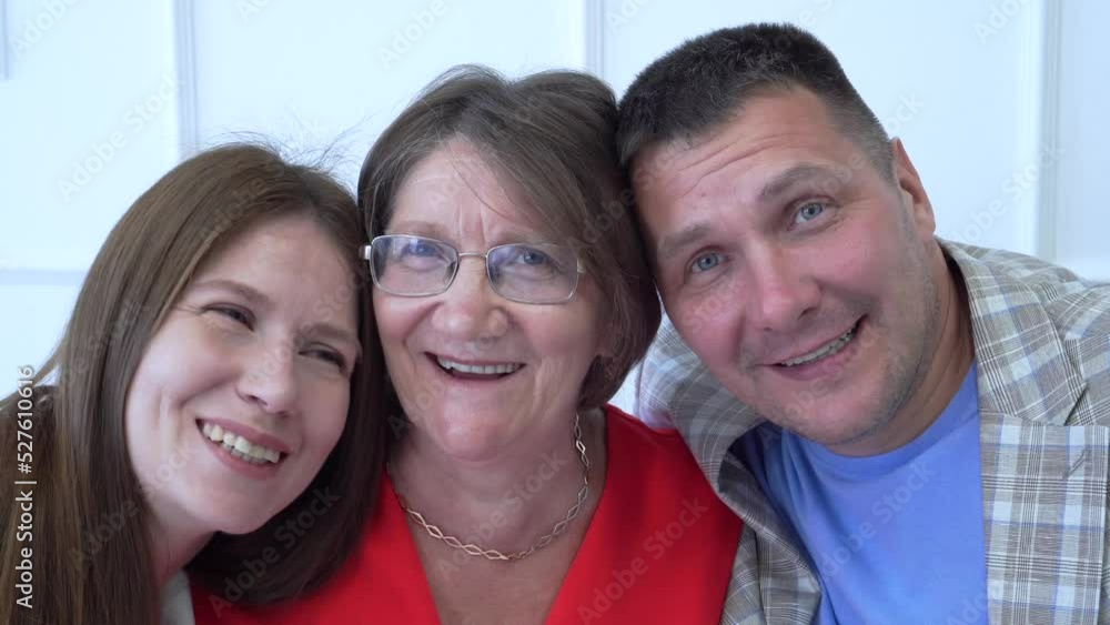 Close-up Family portrait. Adult son and daughter hug an elderly mother, look at the camera and laugh. Family values, studio photo Close-up Family portrait. Adult son and daughter hug an elderly mother, look at the camera and laugh. Family values, studio photo
