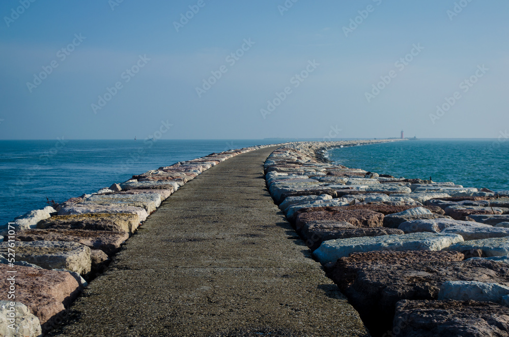 La strada che porta al  faro rosso di San Nicoletto al Lido di Venezia circondato dai frangiflutti di cemento