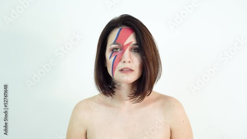 red and blue lightning bolt on her beautiful face. Beautiful girl with original make-up on a white background. Studio photo.