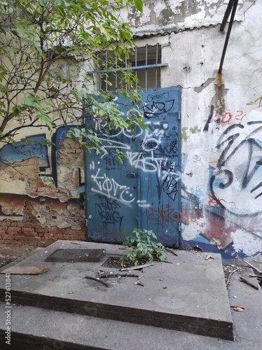 Fotografia a neglected corner, blue doors and graffiti on the walls