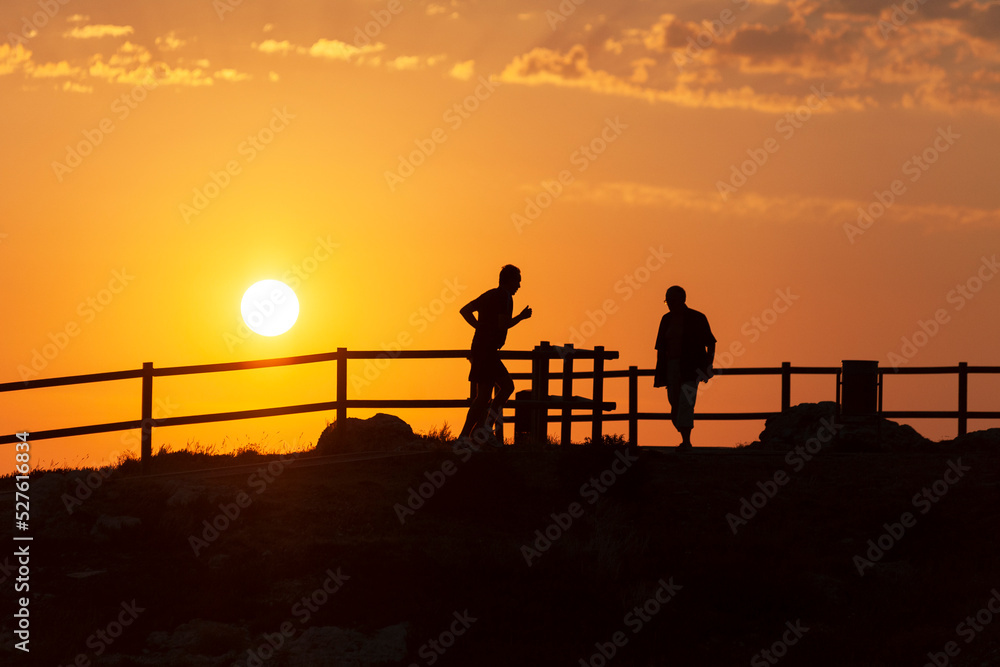 Sunset with contrasted runner and fence silhouette