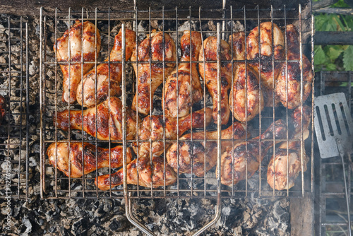 Meat on barbecue grill. Grilled chicken legs or drumsticks. Сooking on the grill in the garden. Shallow depth of field