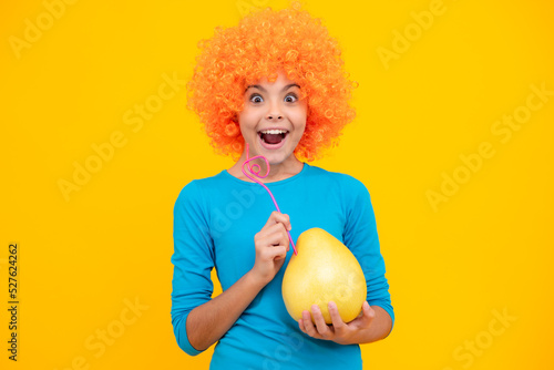 Funny teenage girl hold citrus fruit pummelo or pomelo  big grapefruit isolated on yellow background. Summer fruits. Excited teenager  glad amazed and overjoyed emotions.