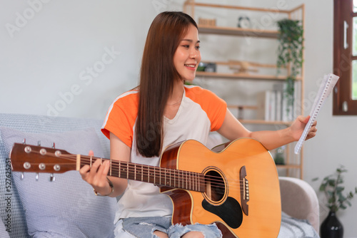 Guitar and singer concept, Young asian woman reading lyrics and playing music with acoustic guitar