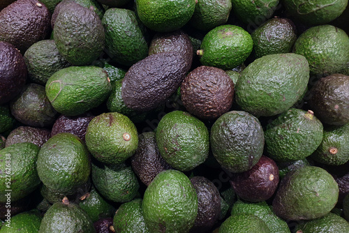 Avocado background. Heap of fresh green avocado on market stall.