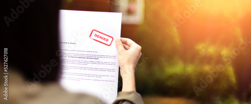 Young brunette long hair girl cries hysterically after being denied a mortgage loan.Depressive sad state female millenial holding  rejection document copy space banner