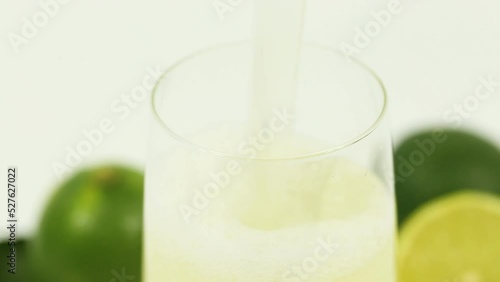 This vibrant and zesty stock photo features limes and freshly squeezed lime juice on a crisp white background, ideal for food, beverage, and health-related content.