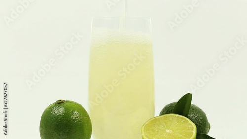This vibrant and zesty stock photo features limes and freshly squeezed lime juice on a crisp white background, ideal for food, beverage, and health-related content.