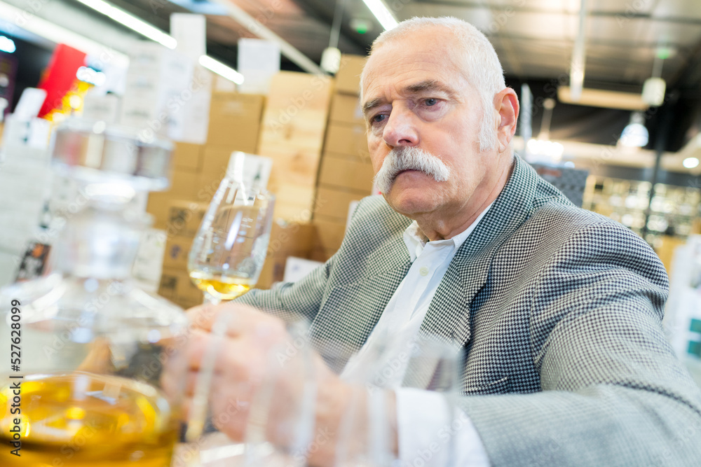 senior man sampling glass of cognac senior man sampling glass of cognac