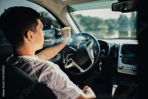 Man smoking a cigarette at the wheel of a car. © stenkovlad