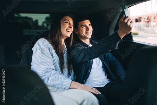 A couple takes a selfie in the back seat of a car while traveling in a taxi.