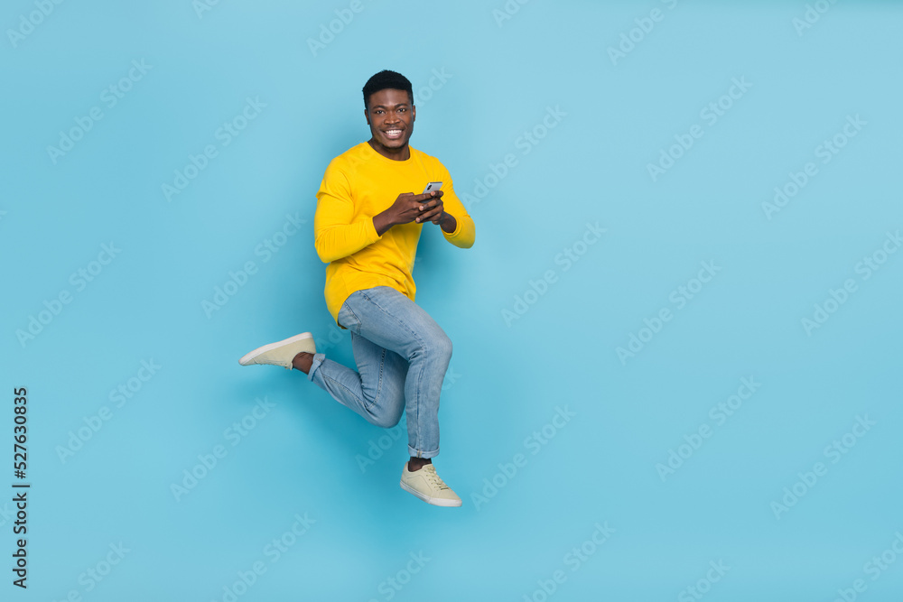 Full length photo of funny millennial brunet guy hold telephone run wear smart casual isolated on blue background Full length photo of funny millennial brunet guy hold telephone run wear smart casual isolated on blue background