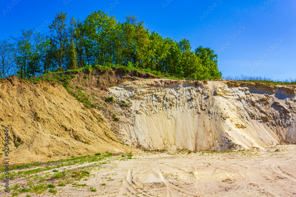 Excavated sand mountains and rubble piles quarry lake dredging pond.